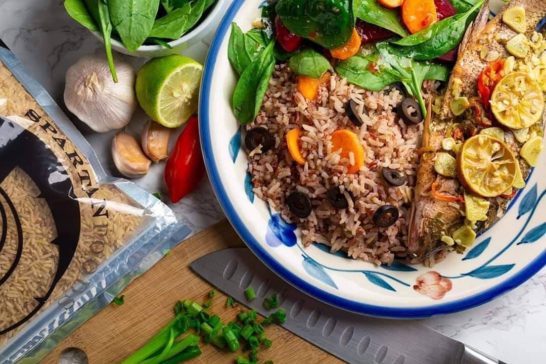 Prepared Caribbean rice and fish plating beside packaged rice